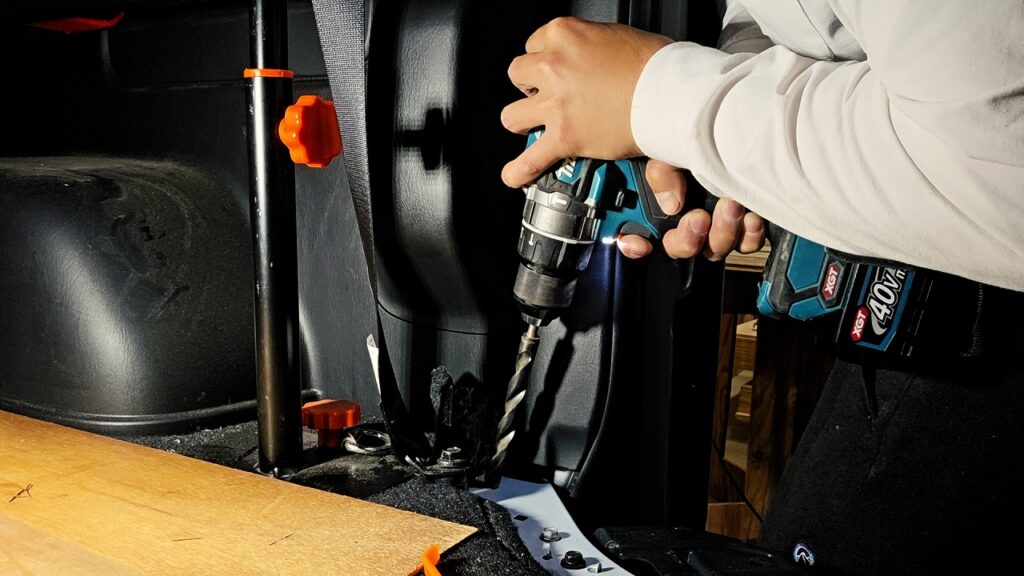 【画像15:ドリルで車内に穴を開けて配線ルートを作る様子】